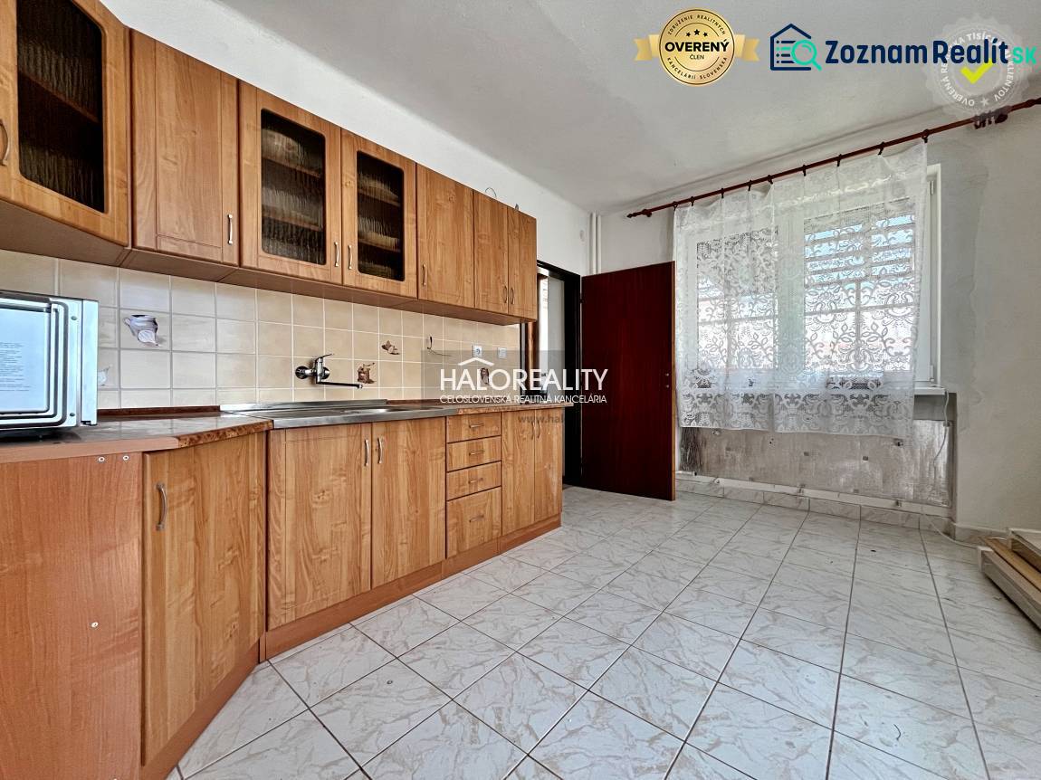 A kitchen with light tiles, wooden cabinets, and ceramic tiles in a family house.
