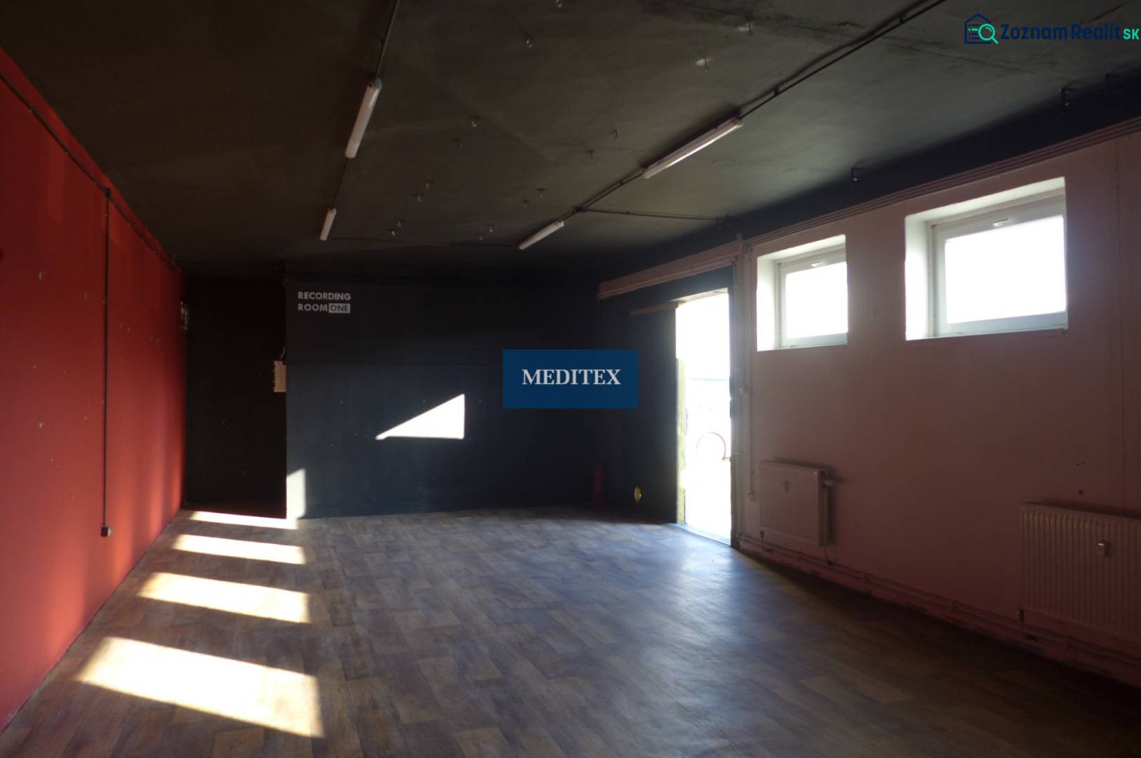 A dark room with red and black walls, a floor with a wooden decor.