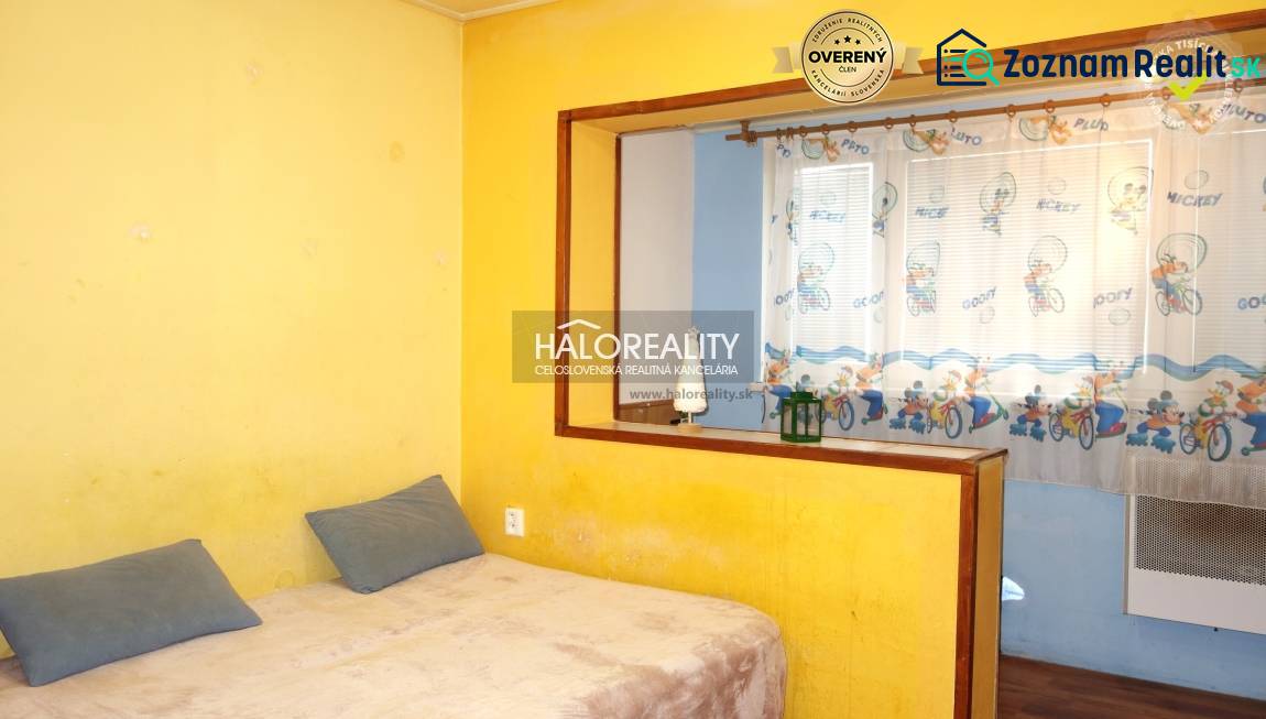 Yellow walls and a bed with pillows in a studio apartment.