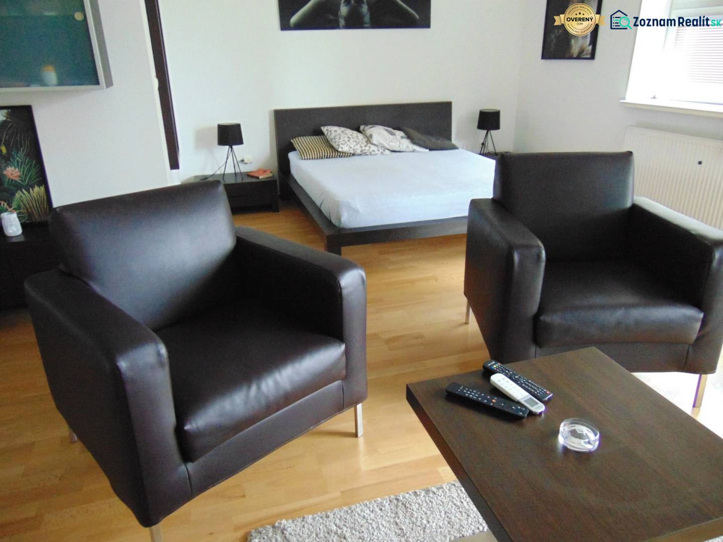 Interior of a 1-room apartment with sofas and a bed on a floor with wooden decor.