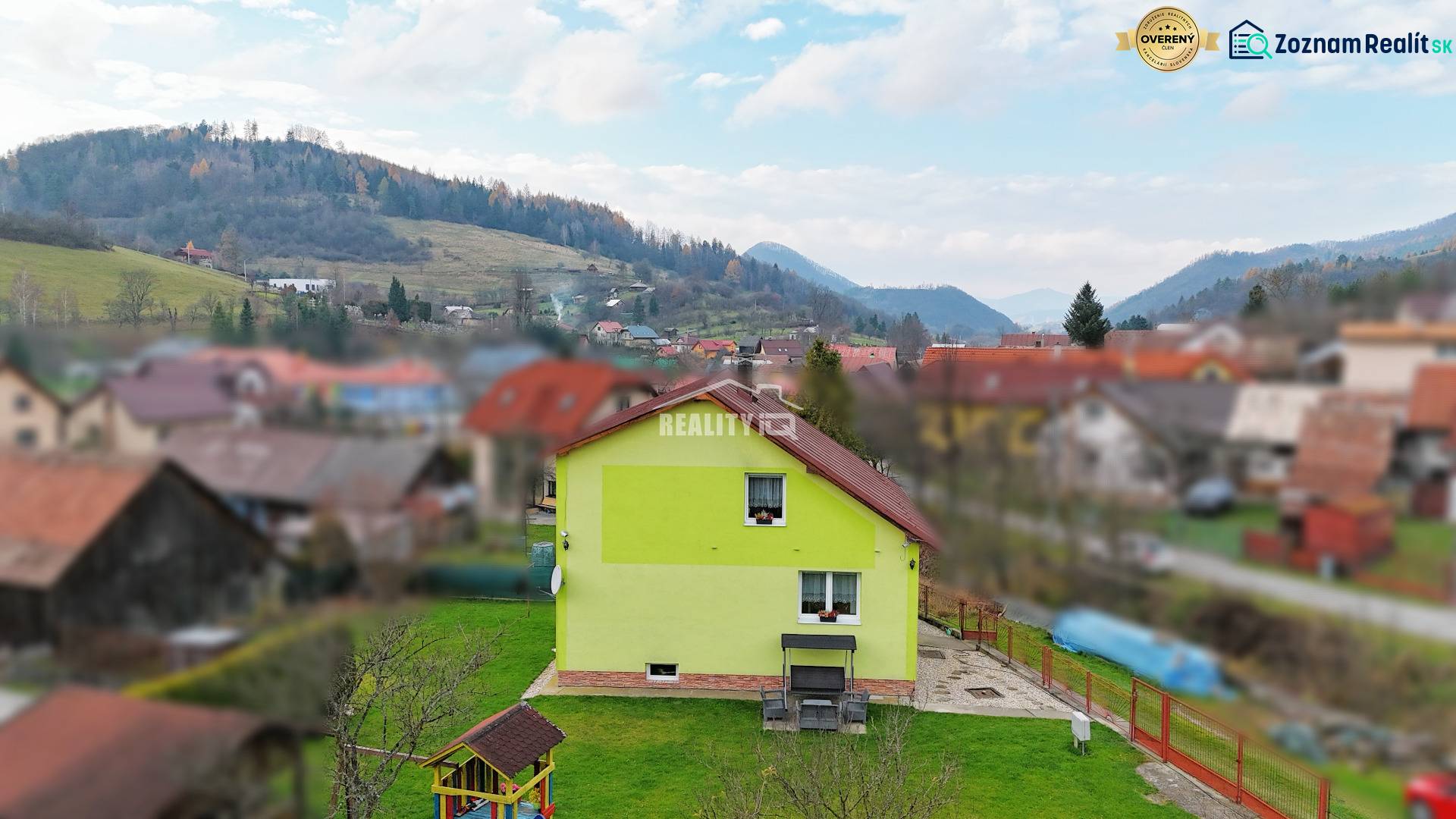 A family house in Kysucké Nové Mesto surrounded by a garden and mountains in the background.