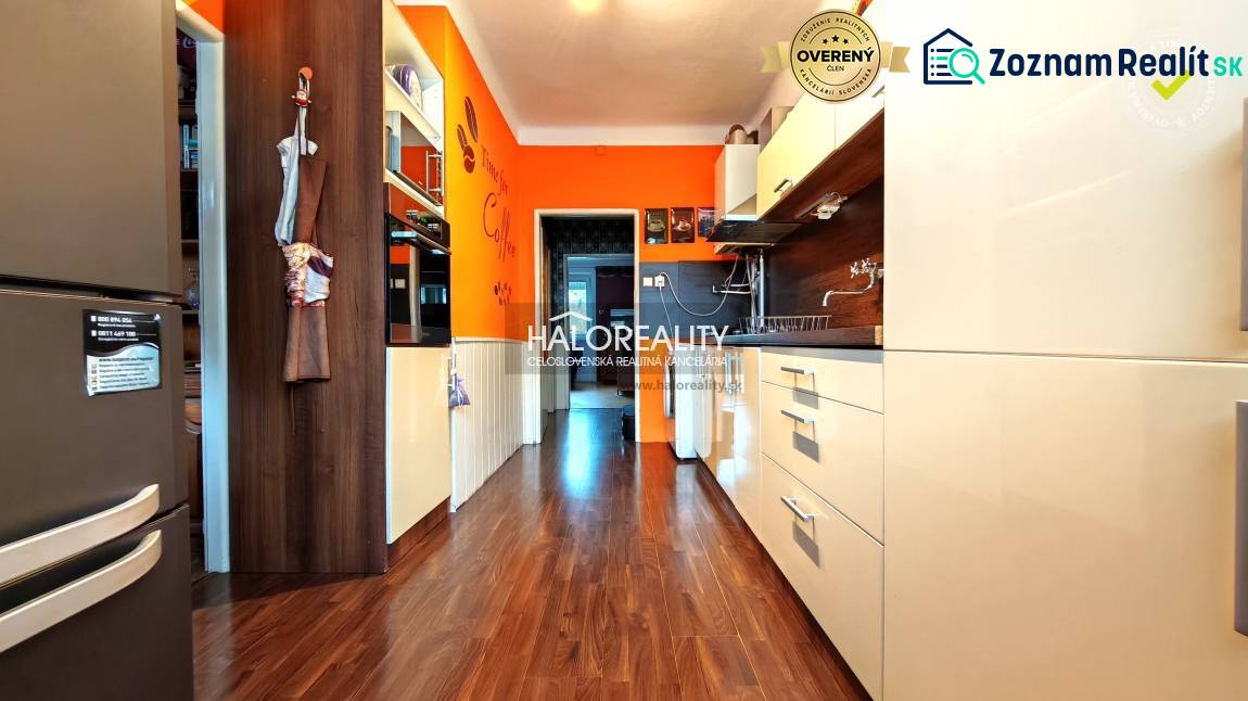 A kitchen with wood-patterned flooring, modern equipment, and orange accents in a 4-room apartment.