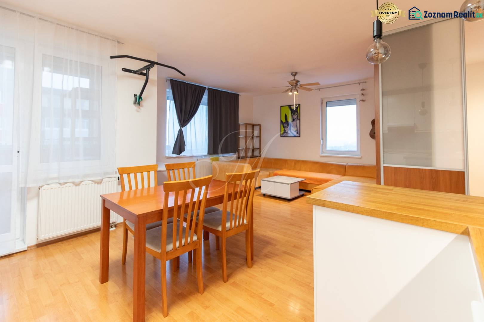Living room in a one-bedroom apartment with wood-patterned flooring, seating, and a dining table.