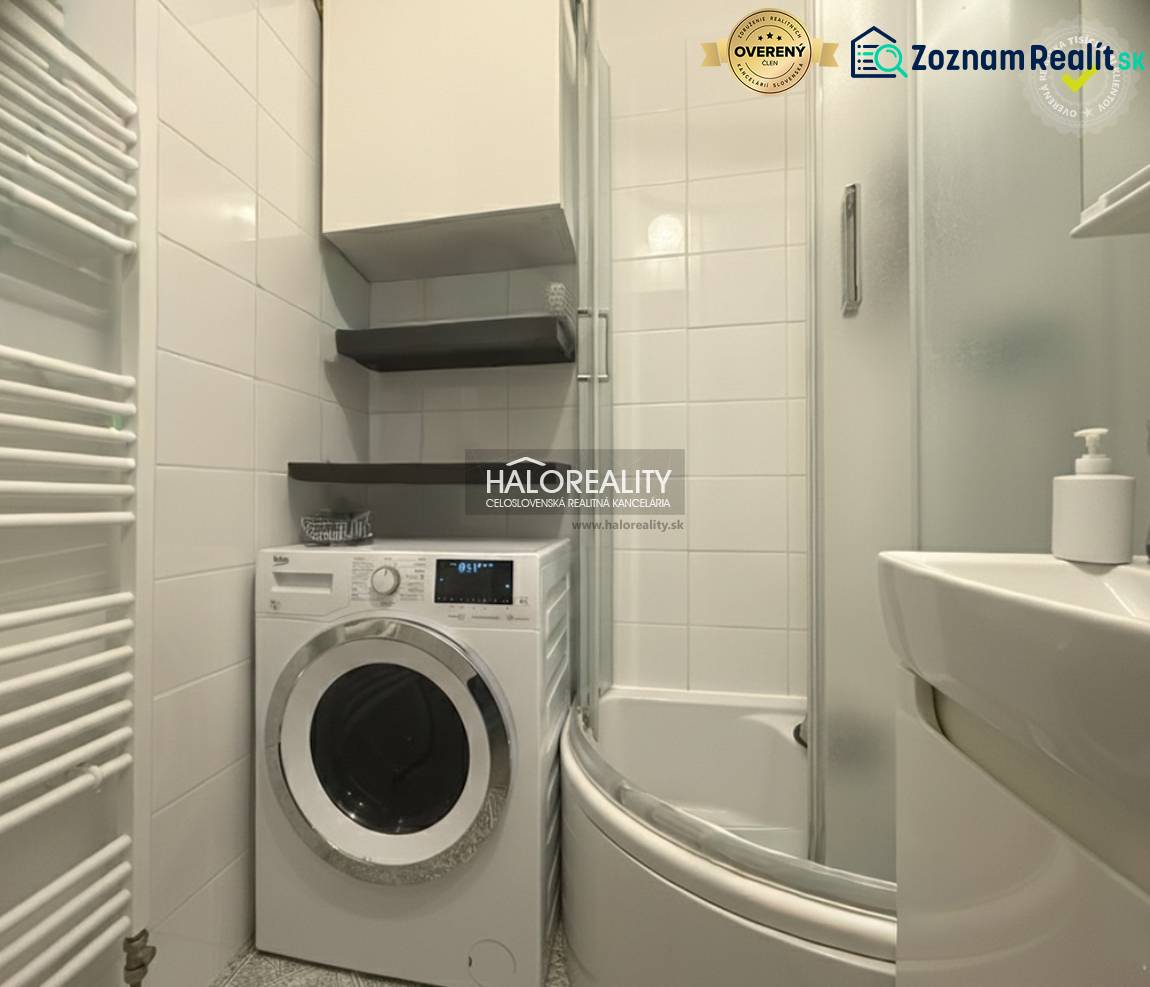 A bathroom in a 3-room apartment with a washing machine, shower, and white tiles.
