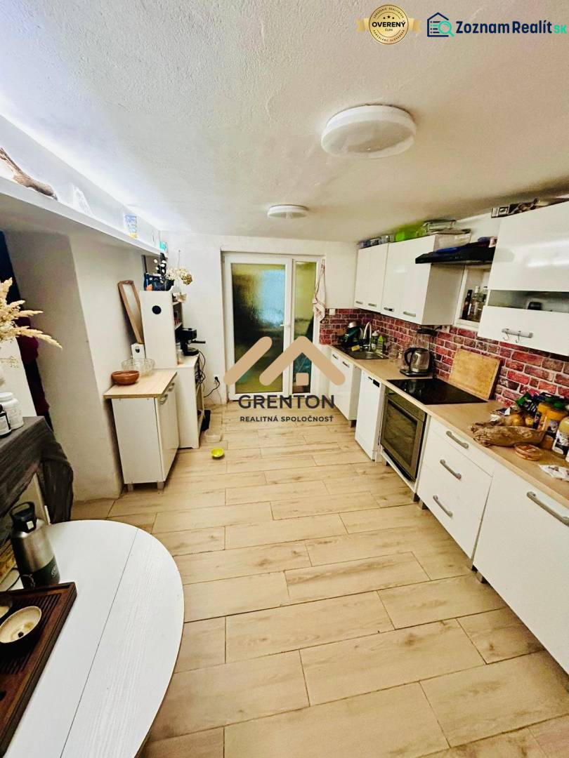 A kitchen in a cabin with a wood-decor floor and white furniture.