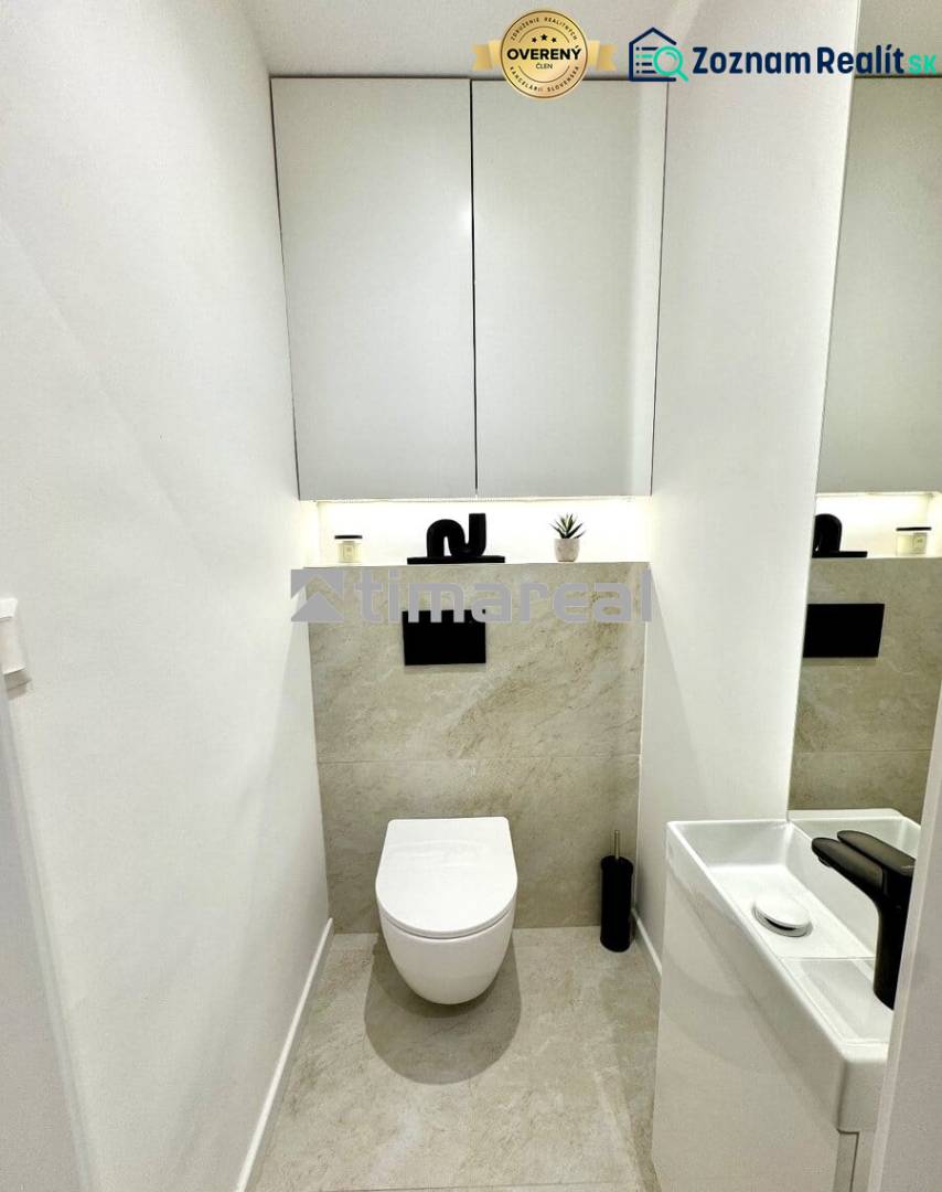 Bathroom in a 4-room apartment with a simple sink and wall-mounted toilet, light tiles.