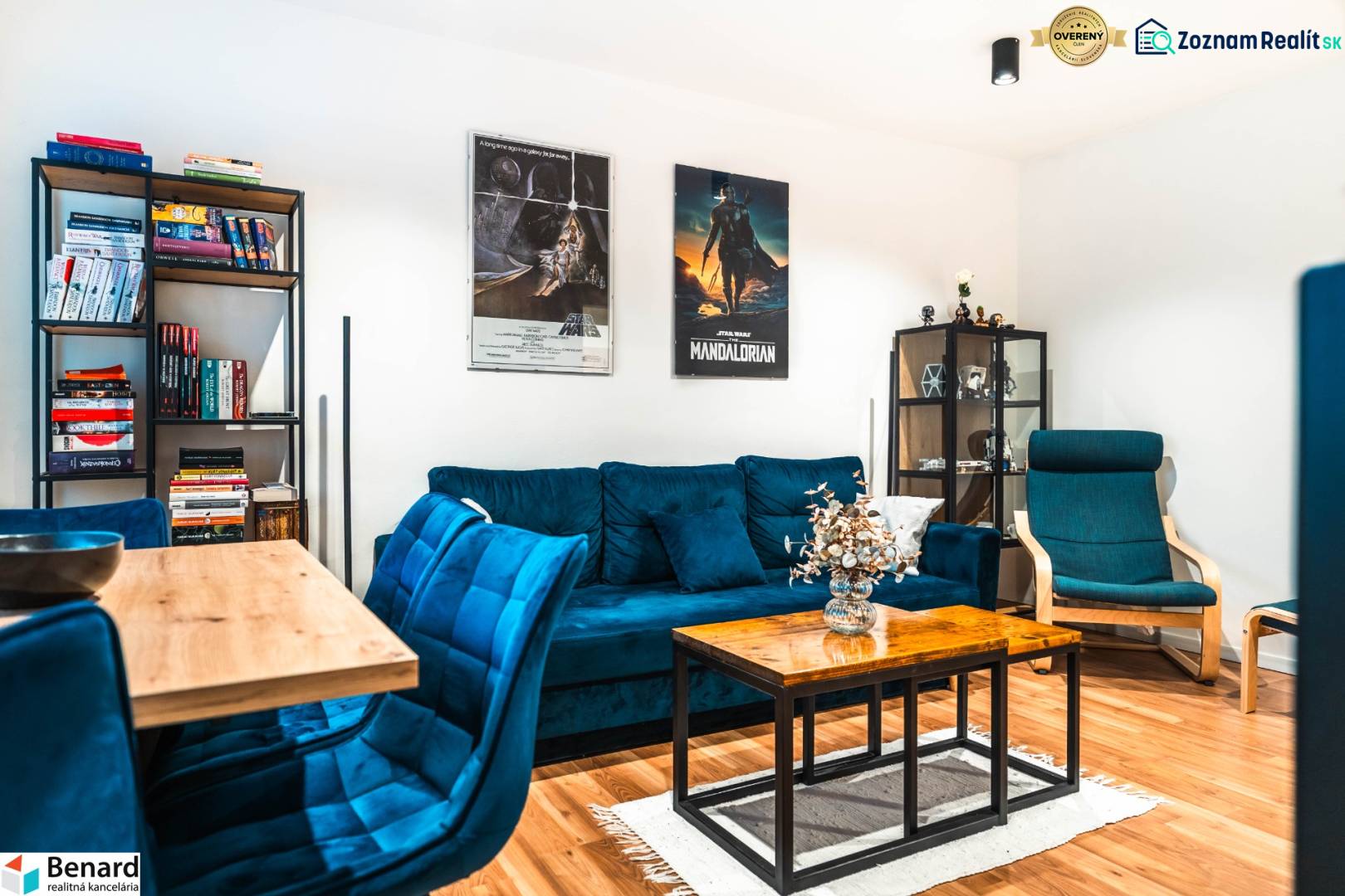 Living room of a two-room apartment with a blue sofa, a bookshelf, and a wooden decor floor.