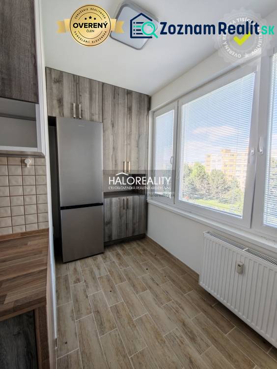 A kitchen in a 2-room apartment with a light wood-patterned floor and large windows.