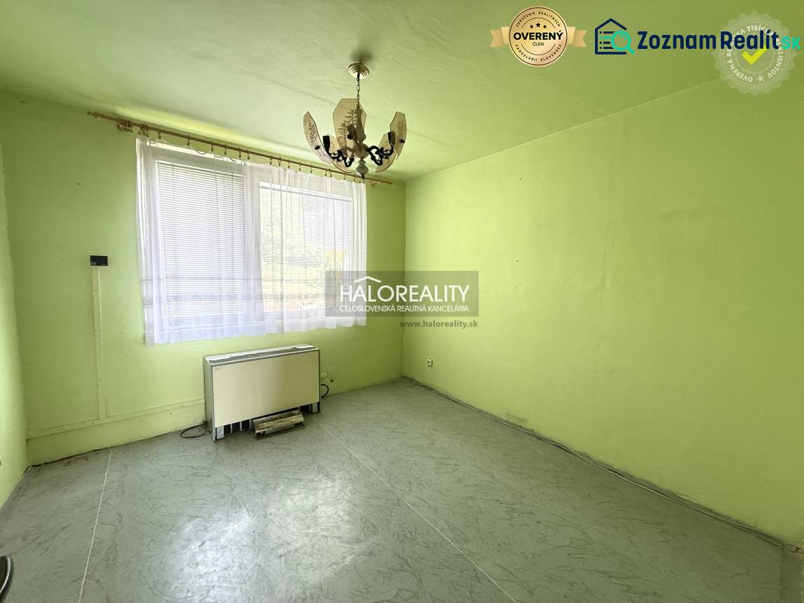 A room with a chandelier, a window, and a heating unit in a three-room apartment.