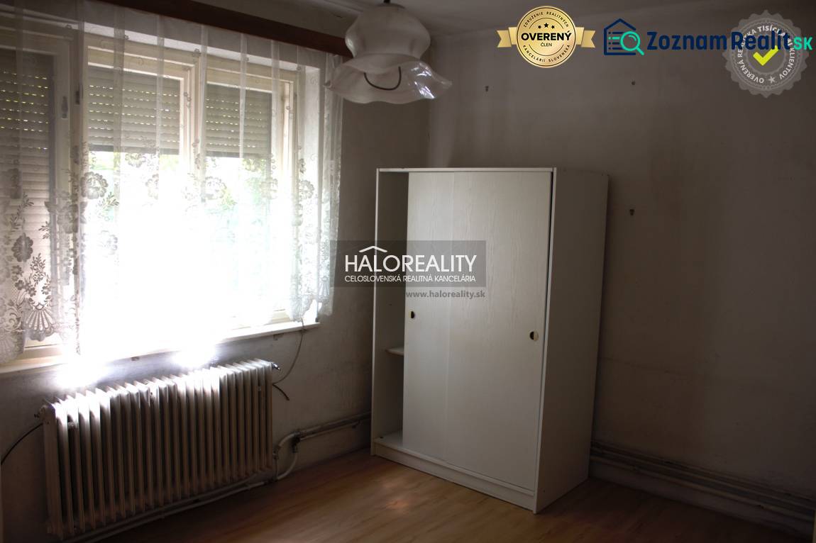 A room in a family house with a large window, a radiator, and a white wardrobe.