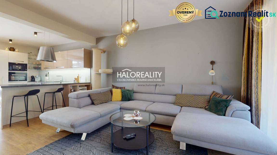 A spacious living room in a family house with a sofa, a kitchenette, and a wooden decor floor.