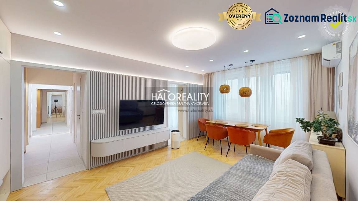 Living room in a 3-room apartment with a TV on the wall, a sofa, and a dining table.