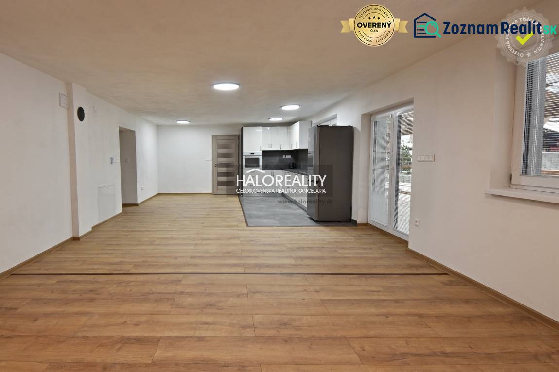 Living room in a family house with a kitchen, wooden decor flooring, white walls.