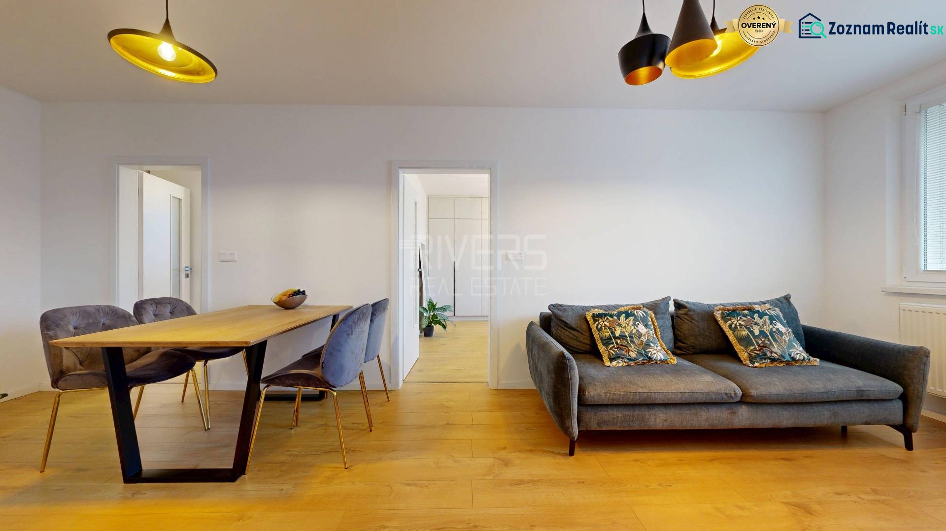 Living room of a 3-room apartment with a lounge area, dining table, and wood-patterned flooring.