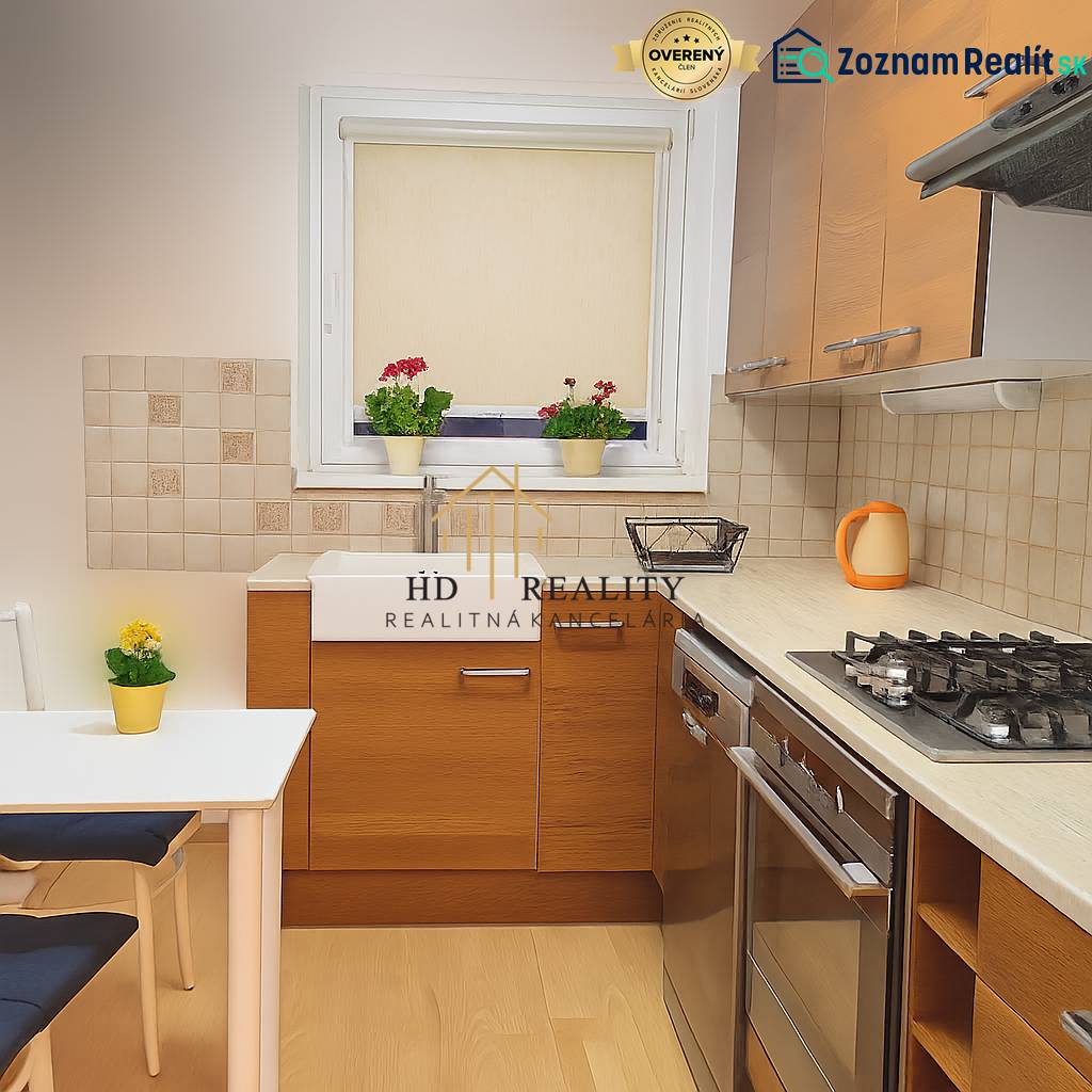 A kitchen in a 4-room apartment with a stove, sink, flowers on the windowsill, and a floor with a wooden decor.