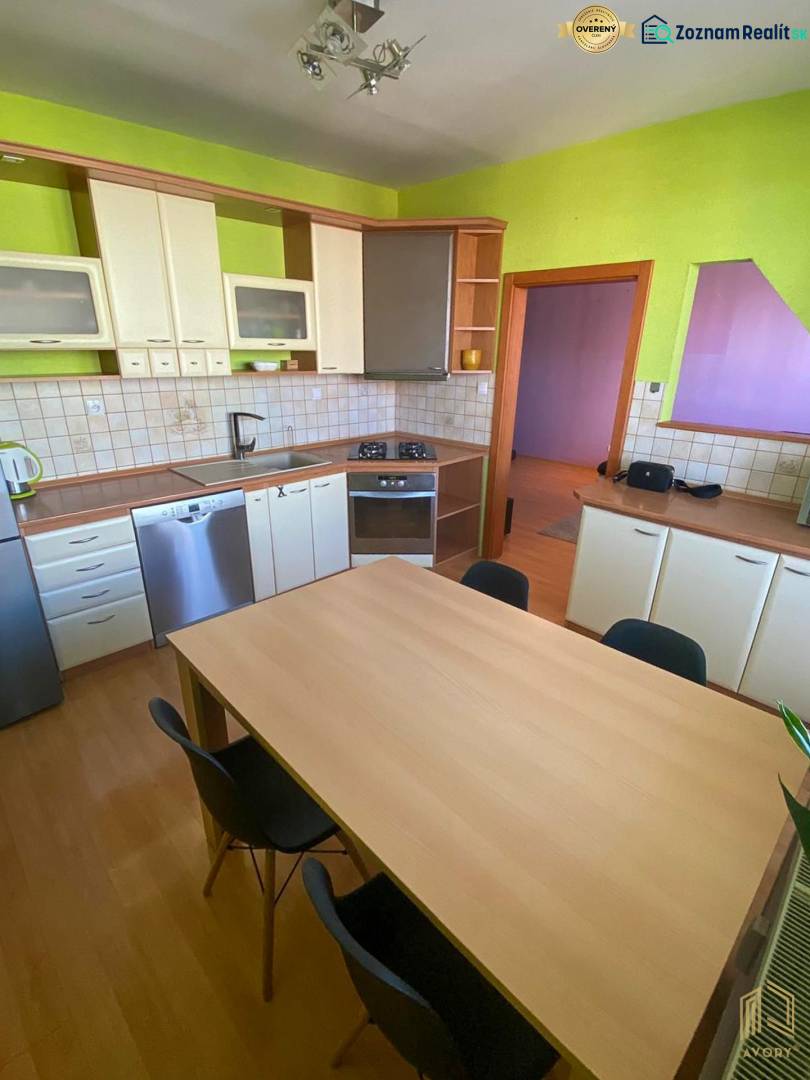 A kitchen in a 3-room apartment with a wooden decor floor and green walls.