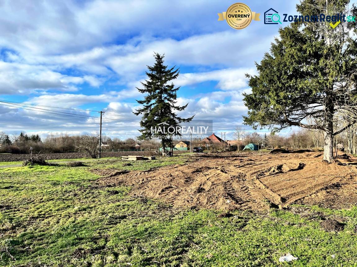 Residential plots in Ondrejovce with grassy areas and trees under a blue sky.