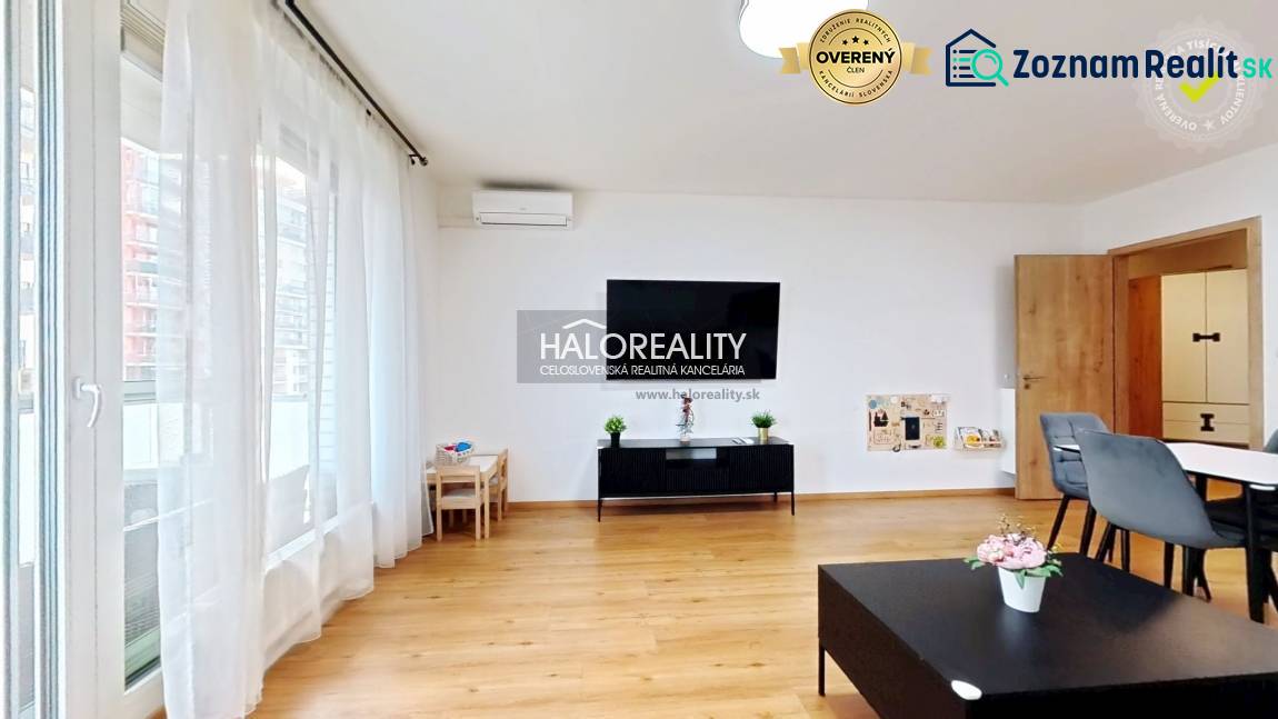 Living room in a two-room apartment with a wooden decor floor, large window, and dining table.