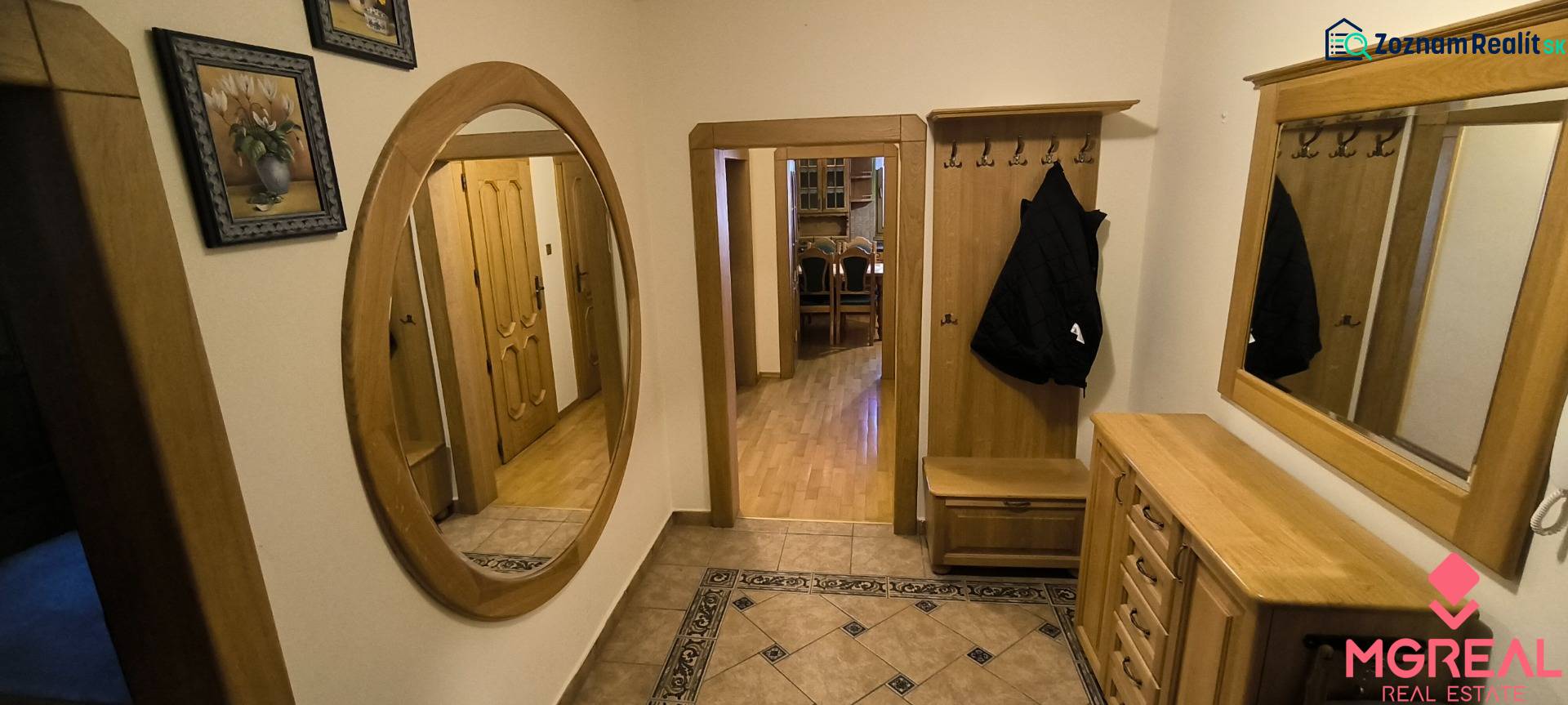 A hallway with a wooden decor floor, a mirror, and stylish furniture in a 3-room apartment.
