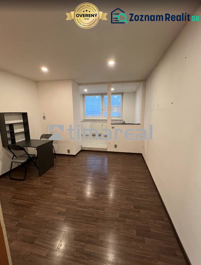 A room in a one-room apartment with a wooden decor floor and a table.
