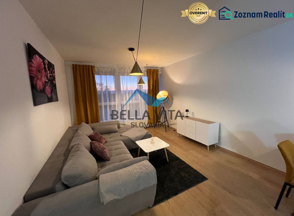 Living room in a two-room apartment with a sofa and wooden decor flooring.