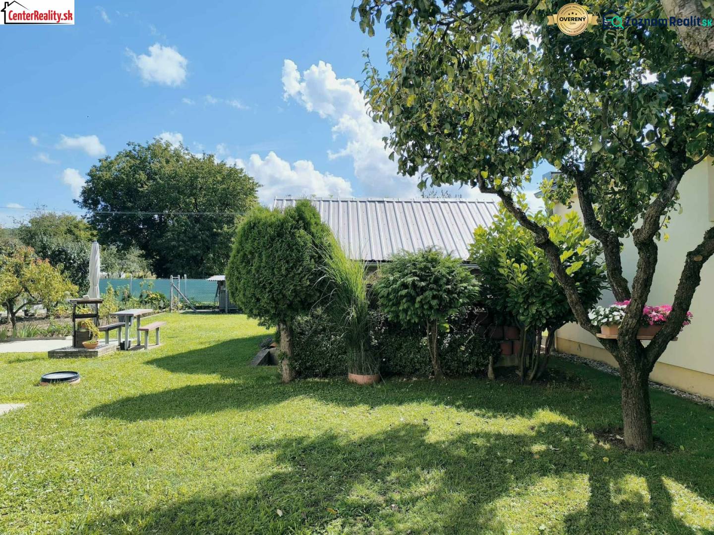 A garden of a family house in Partizánske with a well-maintained lawn, trees, and a seating area.