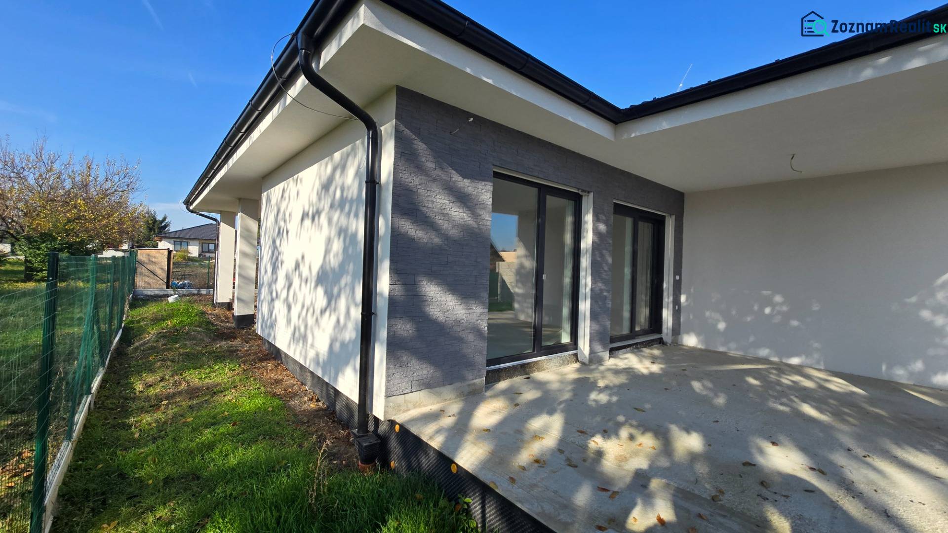 A family house in Piešťany with a terrace and a garden, enclosed by a green fence.