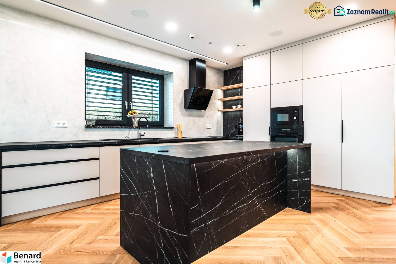 A kitchen in a family house with a marble island and a wood-patterned floor.