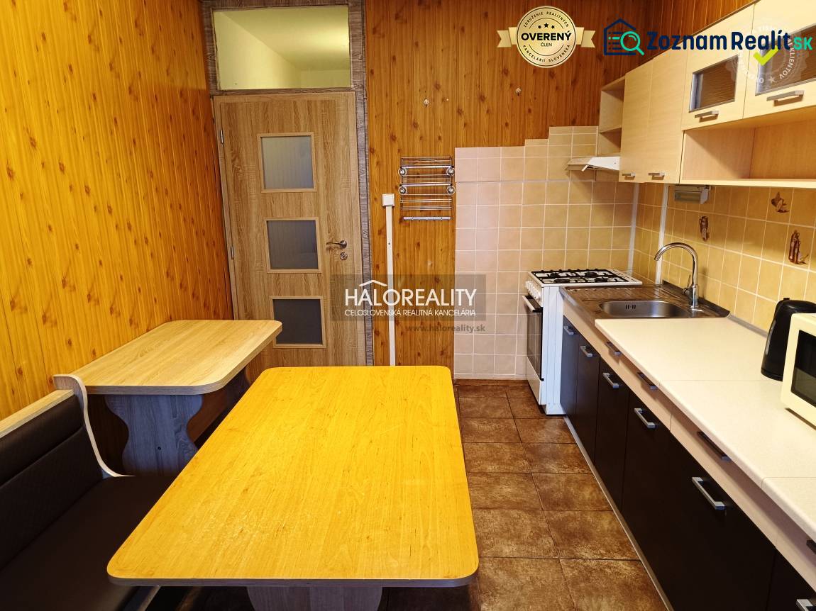 A kitchen in a 3-room apartment with a wood-patterned floor, a table, and a built-in bench.