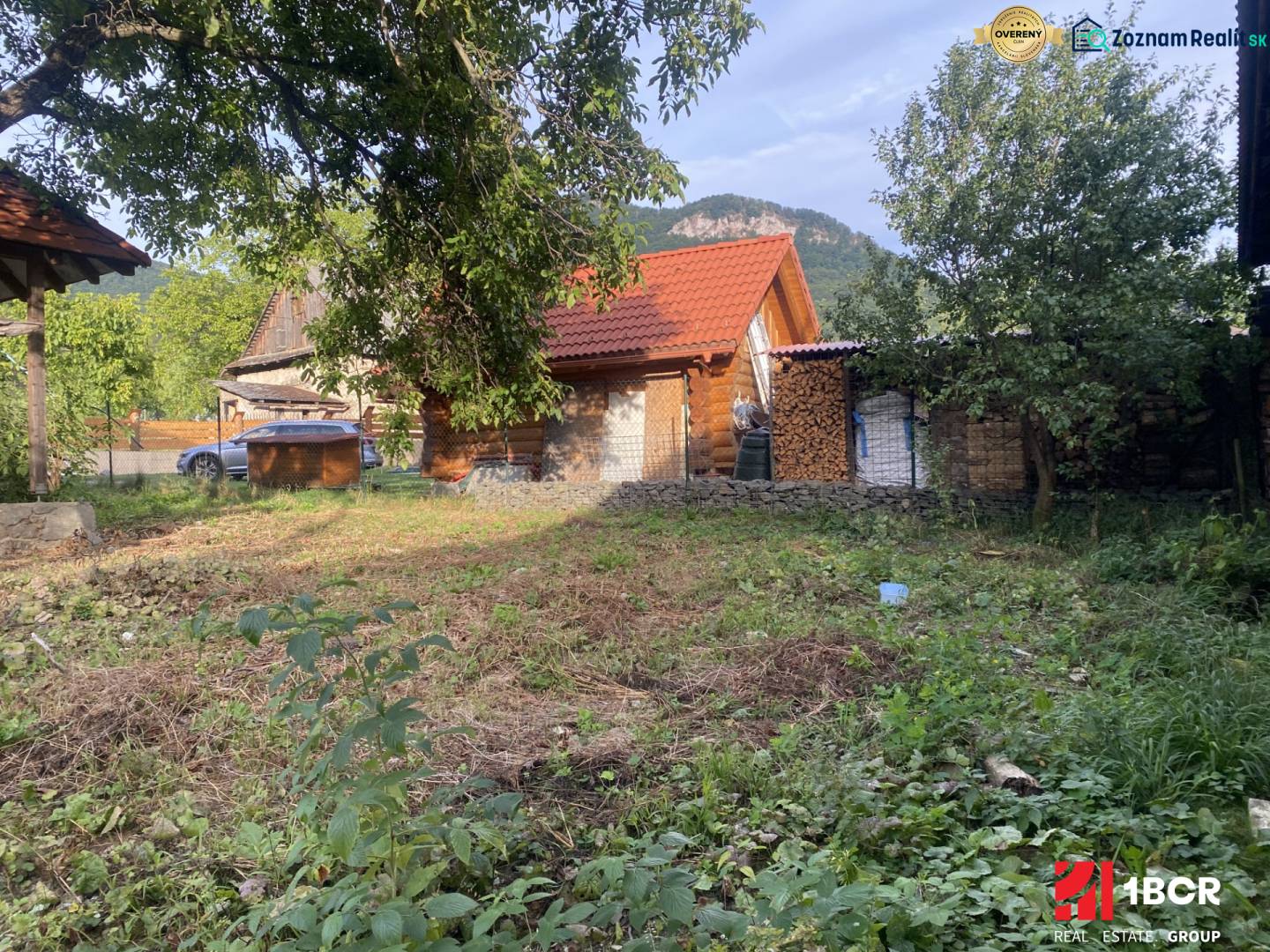 A cottage in Zliechov with a red roof, surrounded by greenery and wood on the property.