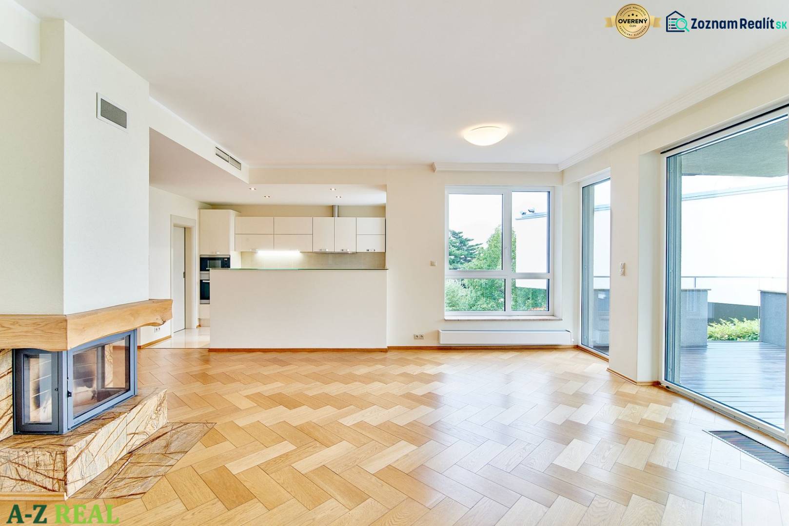 Living room with wood-patterned flooring, fireplace, kitchen, and large windows in a 3-room apartment.