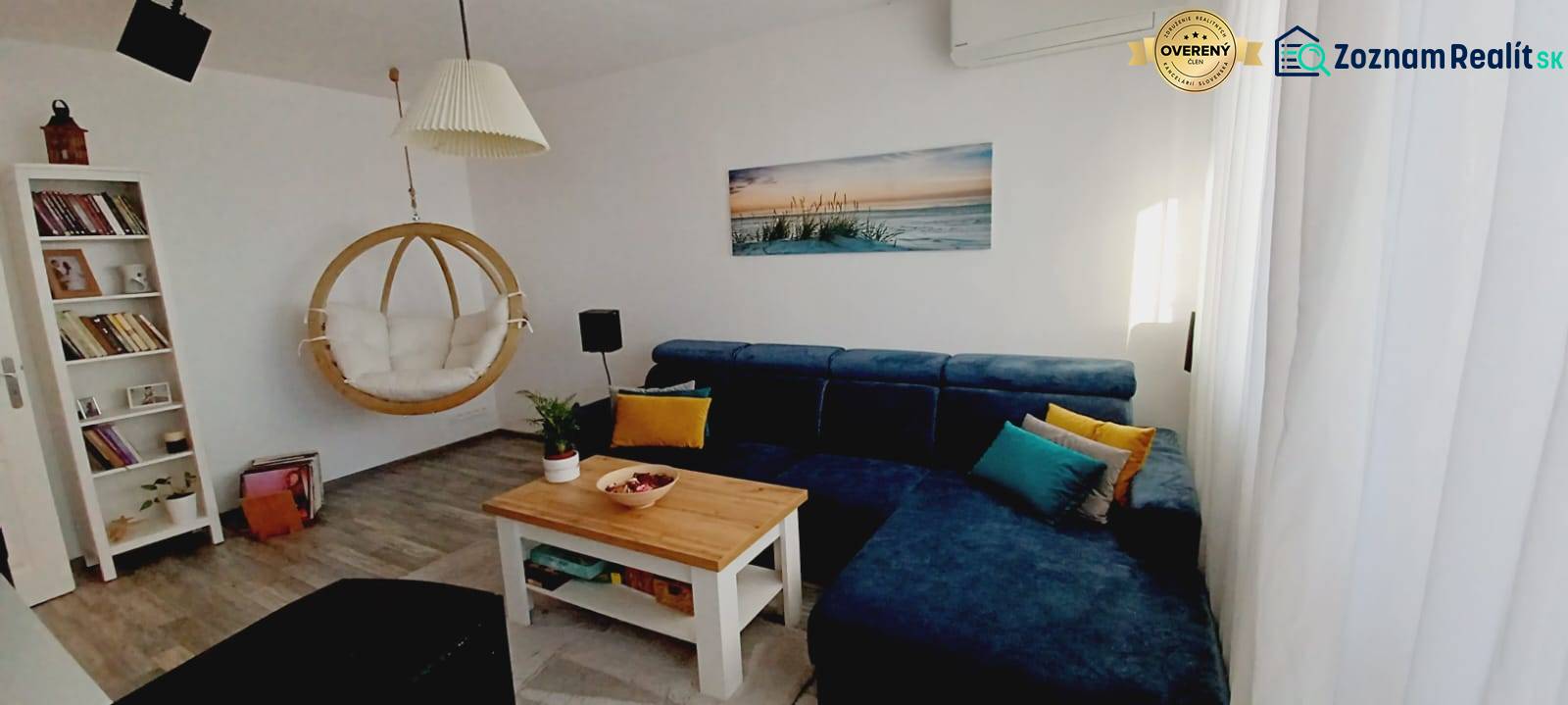 Living room with a blue sofa, swing, bookshelf, and floor with a wood decor.