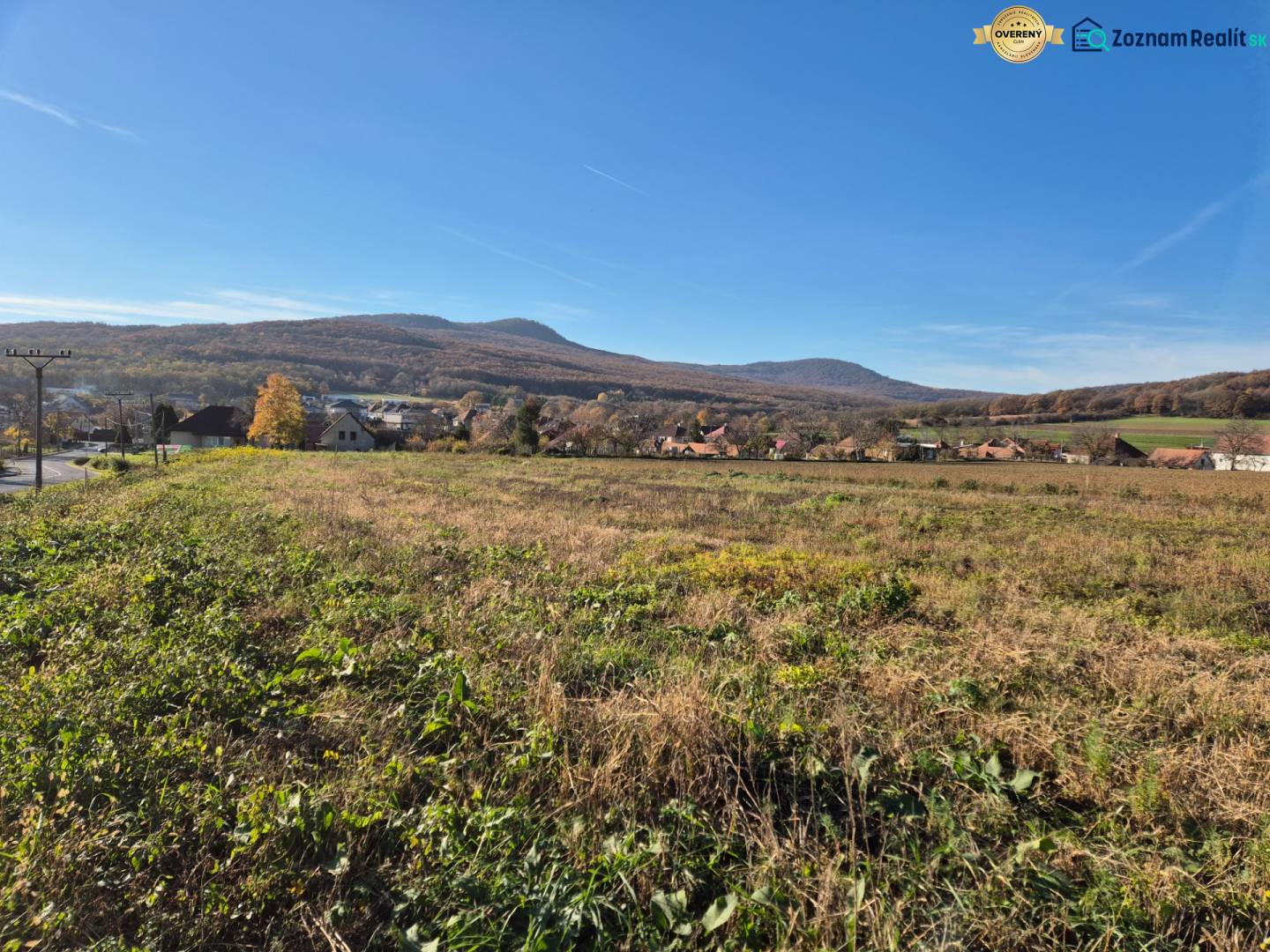 View of the plots - housing in Velčice with hilly landscape in the background.
