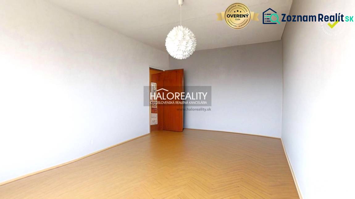 The room in the three-room apartment has a wooden decor floor and a white wall.