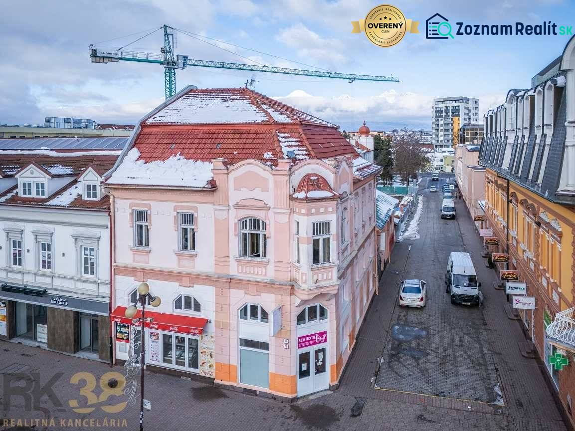 A building in the city of Poprad with historical architecture and a snow-covered roof.