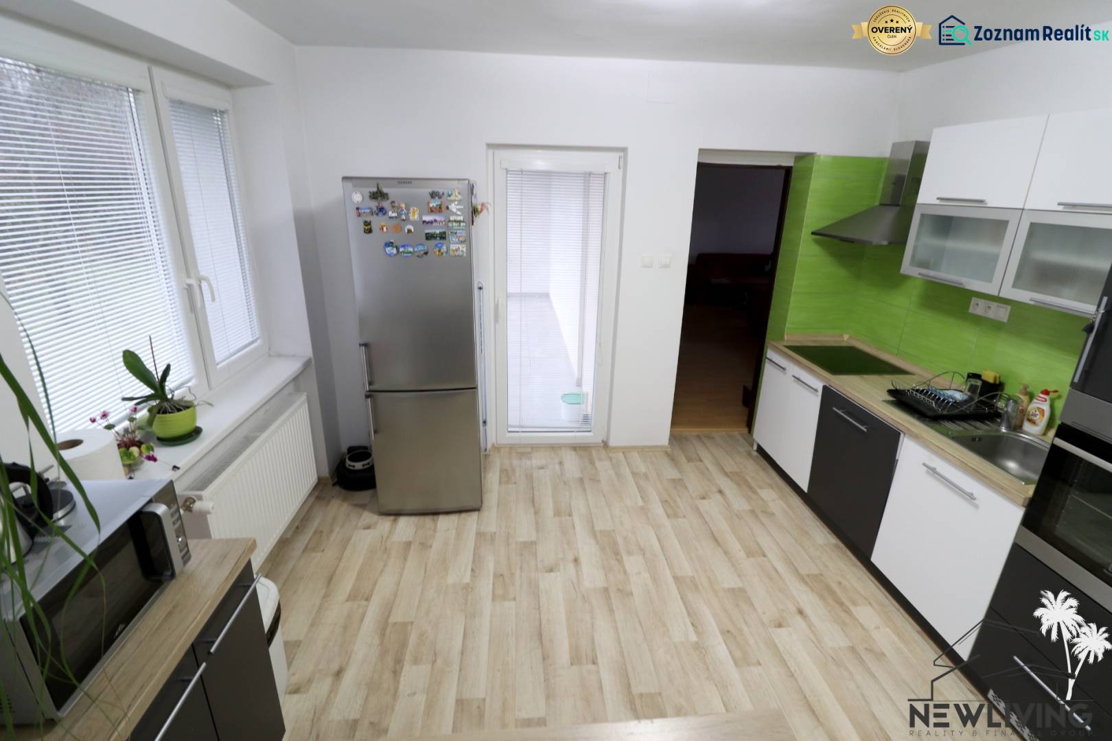 A kitchen in a family house with a wooden decor floor and green tiles.