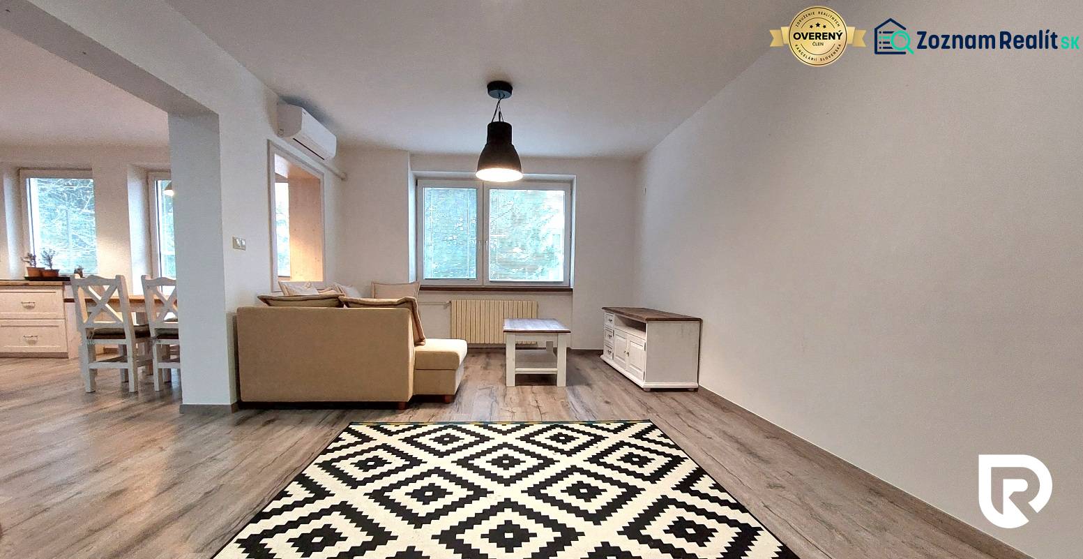 Living room in a 3-room apartment with a sofa, table, wood-patterned floor, and carpet.