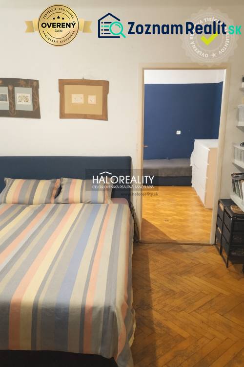 Bedroom in a 3-room apartment with a wooden decor floor and colorful bed linen.