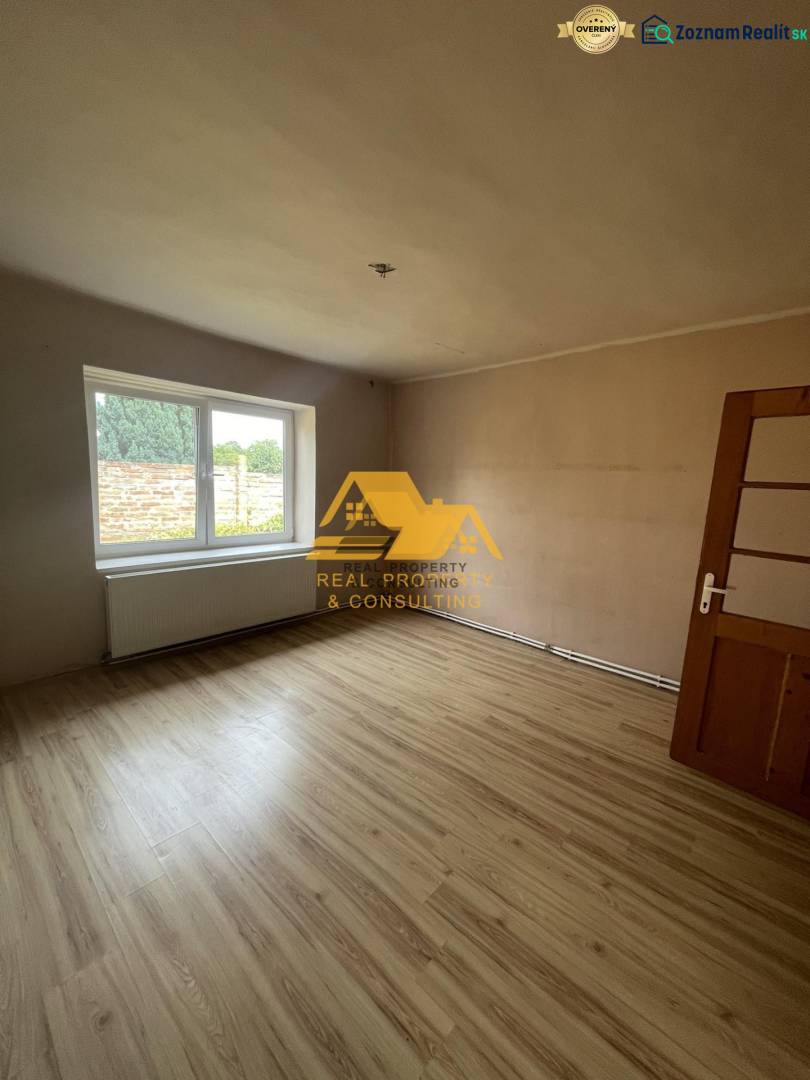A room with a large window and a wooden decor floor in a family house.