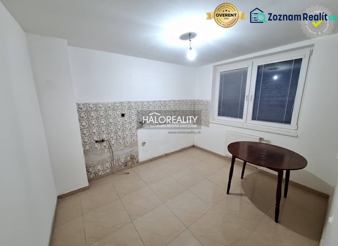 A room in a family house with white walls, a window, and tiles.
