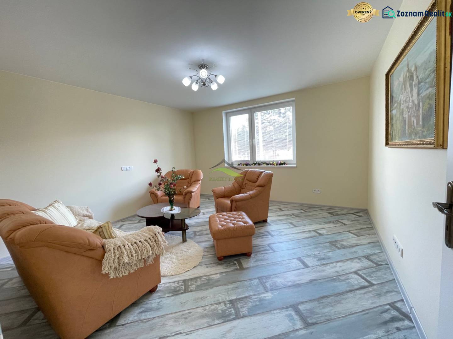 Living room with a brown sofa and wood-patterned flooring in a family house.