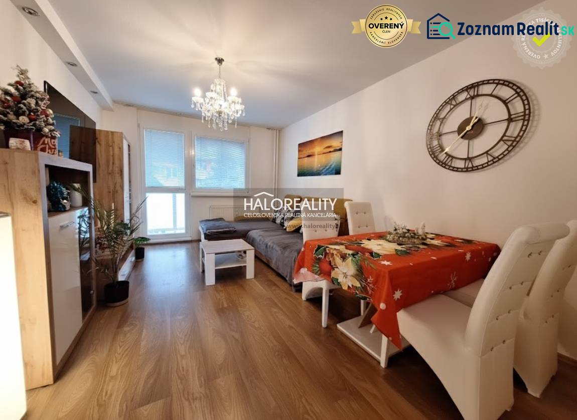Living room of a three-room apartment with a wood-patterned floor and a dining table.