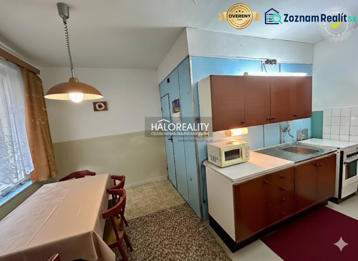 Dining room with a table and kitchen in a 4-room apartment, equipped with cabinets and appliances.