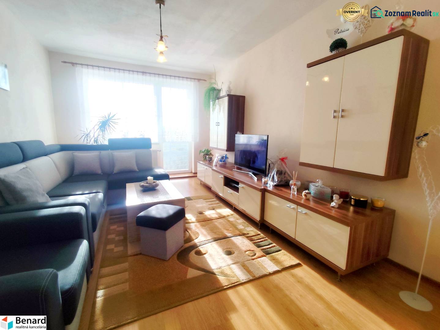 Living room in a 3-room apartment with a sofa, TV, and wooden decor flooring.