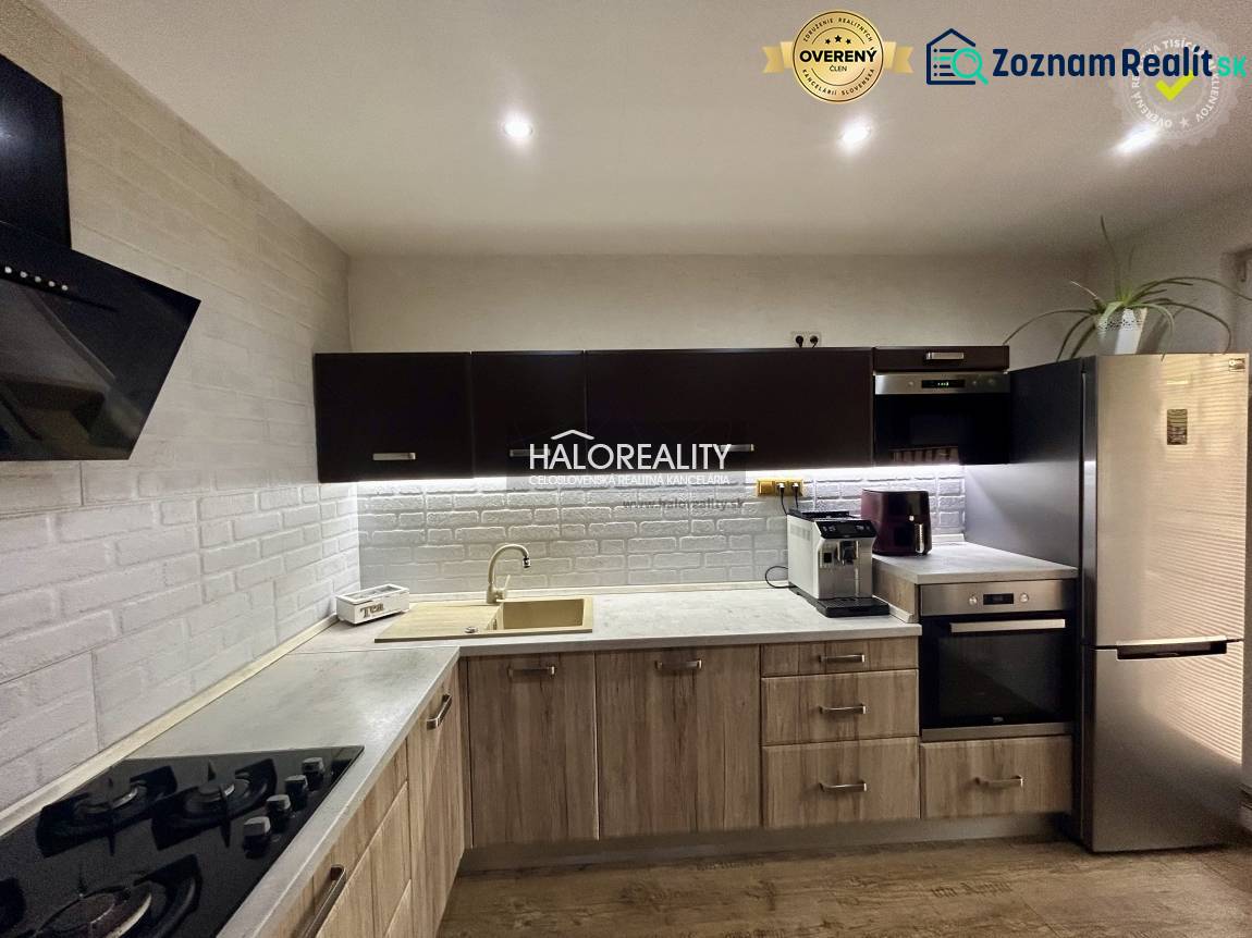 A kitchen in a 3-room apartment with white brick tiles and a wooden decor floor.