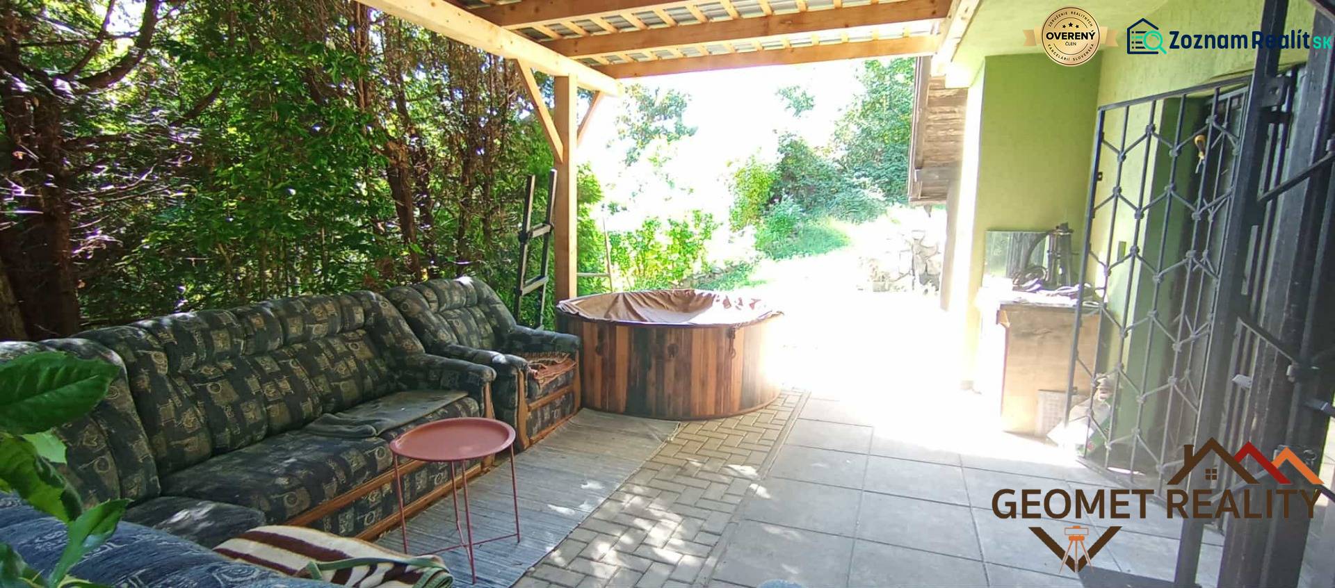 Covered terrace of the cottage in Ružiná with a seating set and surrounding greenery.