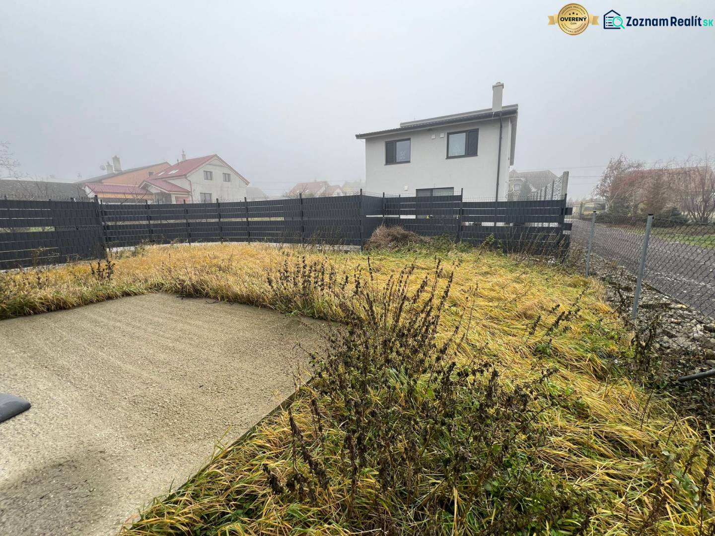 The courtyard of a family house in Plavecký Mikuláš with tall grass and a concrete area.