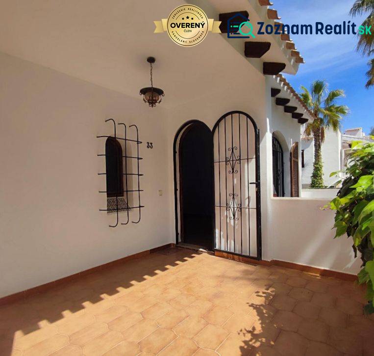 Entrance to a family house with tiles, wrought iron grilles, and a decorative lamp.