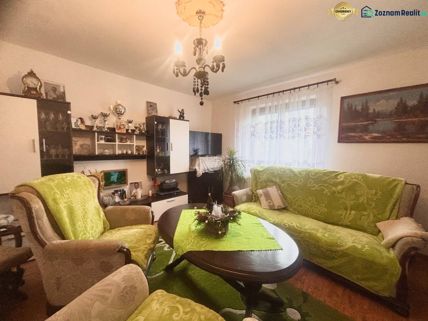 A living room in a family house with wooden decor and green upholstery on the furniture.