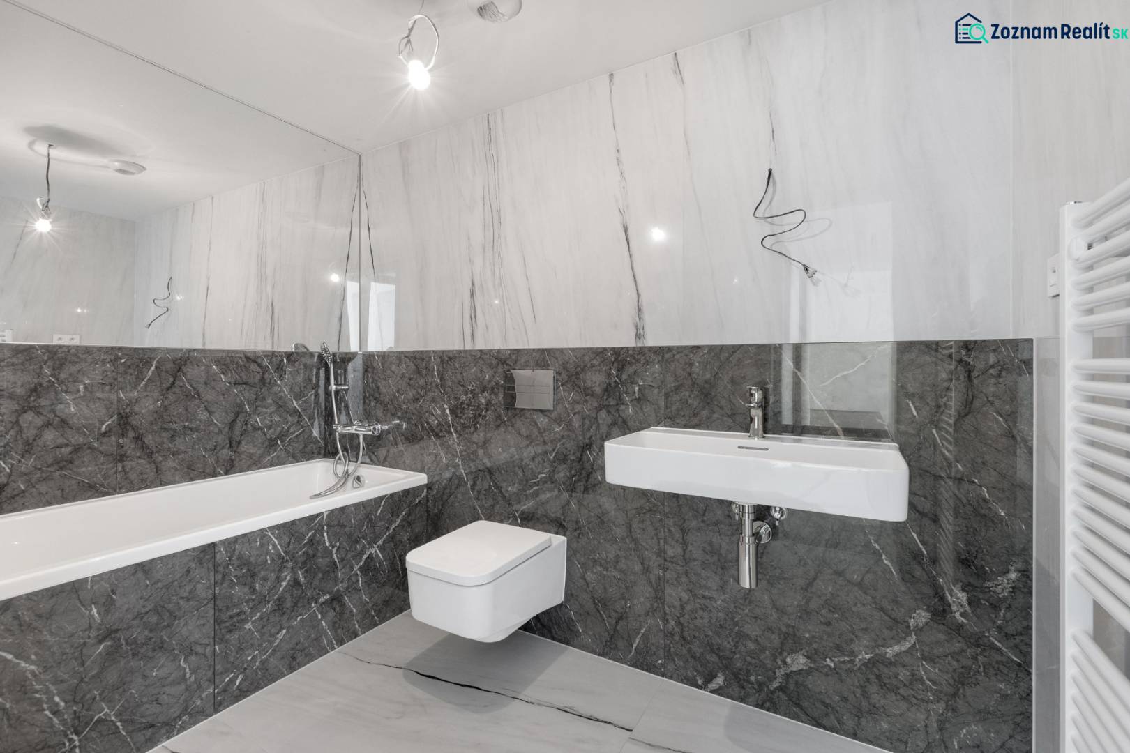 A bathroom with marble tiles, a bathtub, a sink, and a wall-mounted toilet in a 3-room apartment.